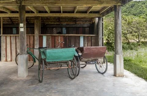 Old cycle rickshaws parked under a house in Kampot in Cambodia Stock Photos