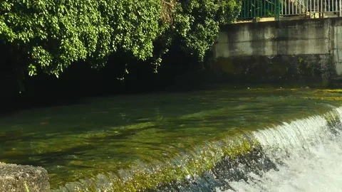An old dam with a small waterfall flowing into a mountain river Stock Footage 126318445