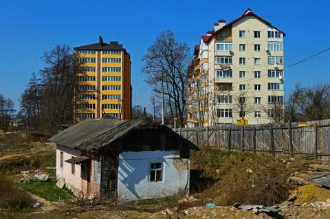 An old damaged building on the background of two new high-rise buildings Stock Photos