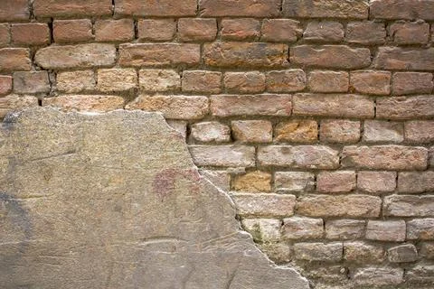 Old damaged red gray brick wall with preserved plaster area. rough surface te Stock Photos