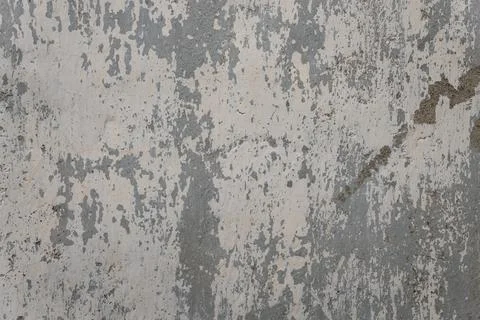 Old damaged wall with peeling gray paint revealing a concrete backing Stock-Fotos