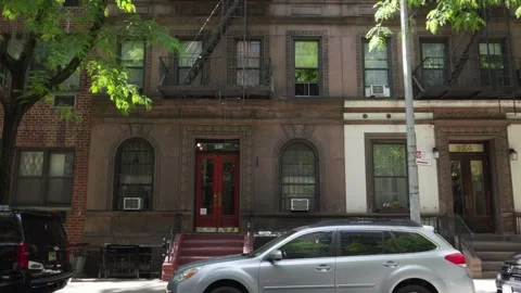 Old dark brownstone building with a rust red stoop double red doors and an o Stock Footage 242365624
