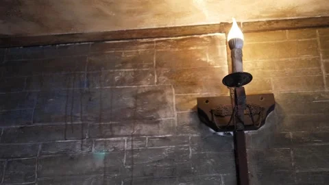 An old dark gray wall with a vintage candle-shaped light bulb in a dark room. Stock Footage 249162710