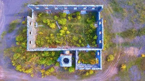 Old decayed outline of a stone building with a chimney and trees growing inside Stock-Fotos