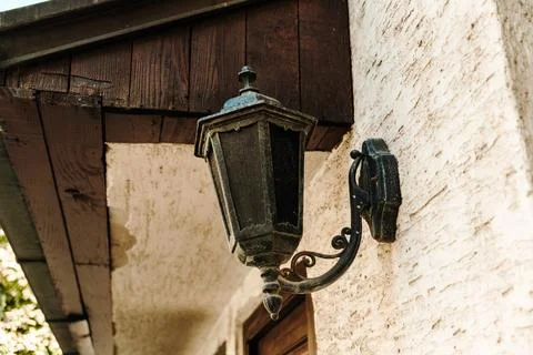 Old decorative wall lantern mounted on a textured house exterior. Vintage lig Stock Photos