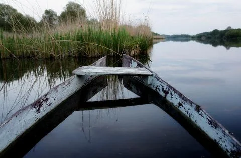 An old decrepit half-sunken boat in the lake in the evening Stock Photos