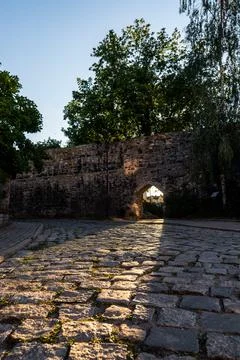 Old defensive stone wall with an arched passage illuminated by sun rays Foto stock