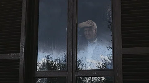 Old depressed man looking the rain behind the window  Video stock 68750205