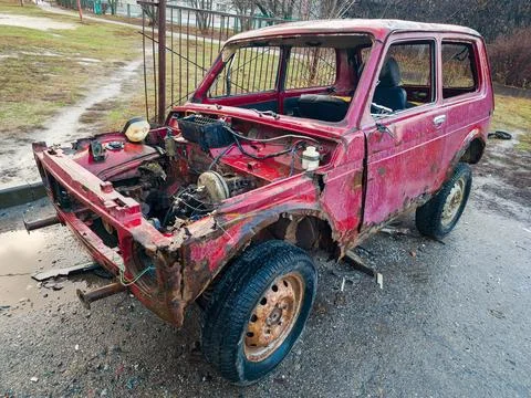 Old destroyed car is red. The concept of danger and disaster. An abandoned .. Stock Photos