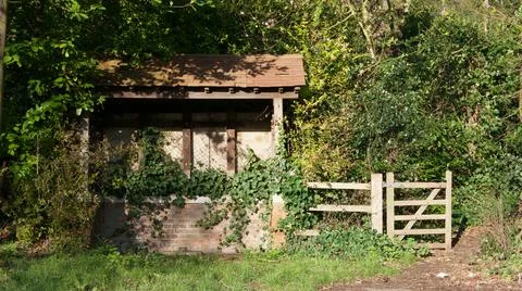 Old dilapidated bus shelter or shack in countryside with gate beside Stock Photos