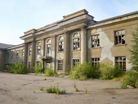 An old, dilapidated multi-storied building with a decaying facade, some board Foto stock