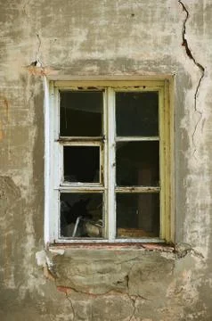 The old dirty broken window on the old dirty wall with cracks. Stock Photos