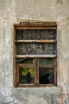 The old dirty broken window on the old dirty wall with cracks. Stock Photos