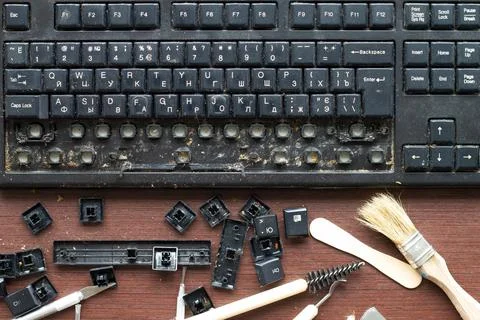 Old dirty computer keyboard with removed keys. The tools for repair and cleaning Stock Photos