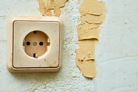 Old dirty electrical socket on the wall before renovation Stock Photos