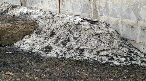 Old dirty melting spring snowdrift reveals remnants of winter near a weathe.. Stock Photos