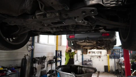 Old dirty oil draining from engine under the car during regular maintenance Stock Footage 295031002