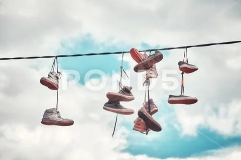 Old dirty shoes hanging on wire. Stock Photos