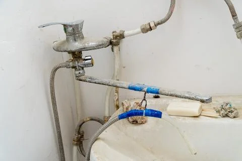 Old dirty sink with wrong connection of pipes and other plumbing Stock-Fotos
