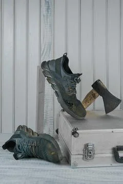 Old dirty torn work boot,worn to holes,wood board,tool box,axe.Durable shoes Stockfoto's