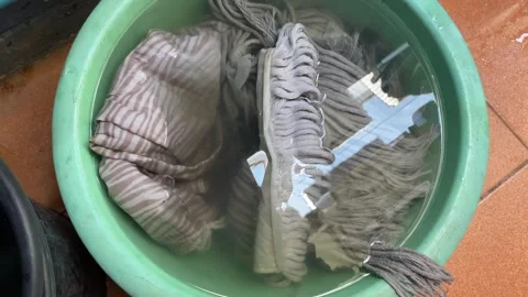 Old dirty white cleaning mop soaking inside green bucket on ground full of water Stock Footage 270277410