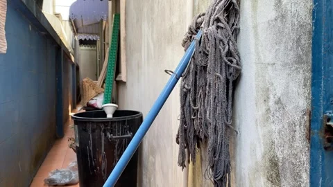 Old dirty white soaking cleaning mop leaning against the wall at home Stock Footage 270277564