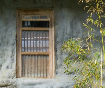 Old dirty window framework with jail bars in a stone wall Stock Photos