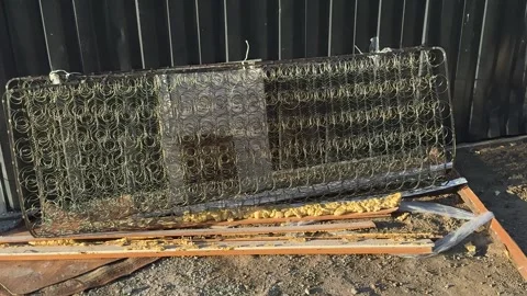 Old discarded mattress spring frame and yellow foam on the ground  스톡 동영상 344041652