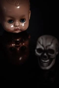 An old doll head with reflection and a skull Stock Photos