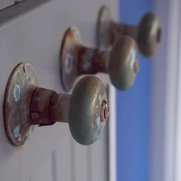 Old door knobs used as coat hangers, exposed to elements Fotos de archivo