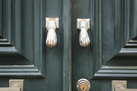 Old doorknocker with hand shape on old wooden door Stock Photos