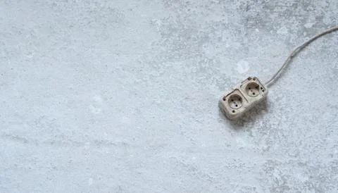 An old double power socket with a wire lies on a grey dirty concrete floor Stock Photos