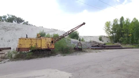 An old dragline in front of a huge mound of sand washed up by a dredger Stock Footage 316234873