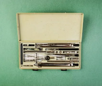 Old drawing tools in a box on a green background Fotos de archivo