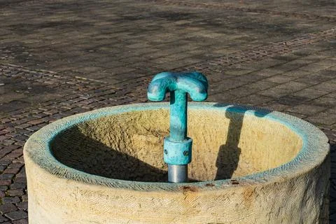 Old drinking spring in a round concrete well in a cobblestone plaza 写真素材