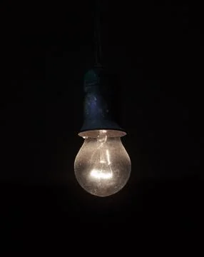 Old dusty light bulb glowing in the dark Stock Photos