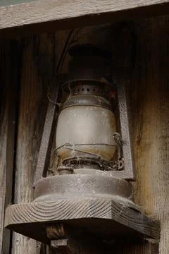 Old dusty oil lantern on rustic wood shelf Stock Photos