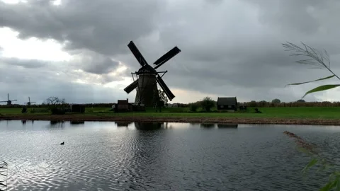 Old Dutch Kinderdijk windmill with moving blades next to the canal. Kinderdijk Stock Footage 145231569