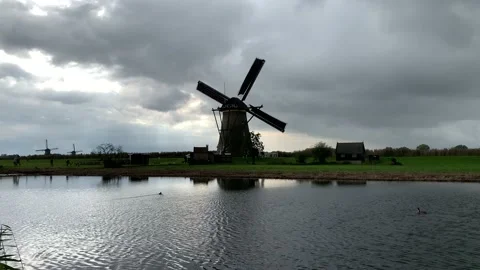 Old Dutch Kinderdijk windmill with moving blades next to the canal. Kinderdijk Stock Footage 145231939