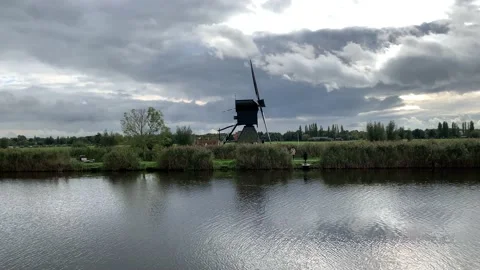 Old Dutch Kinderdijk windmill with moving blades next to the canal. Kinderdijk Stock Footage 145232055