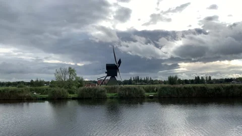 Old Dutch Kinderdijk windmill with moving blades next to the canal. Kinderdijk Stock Footage 145232082