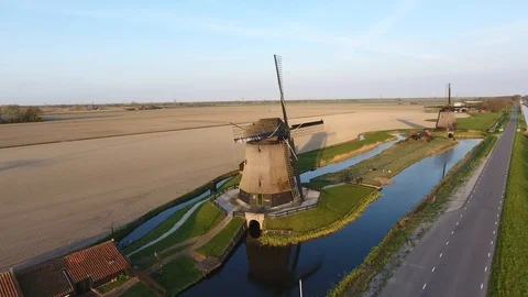 Old dutch windmill with a road on the side and a farm field at the back and some 動画素材 128385243