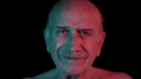 Old, elderly father is smiling with neon, hi tech ultraviolet light. Technolo Stock Footage 134407147