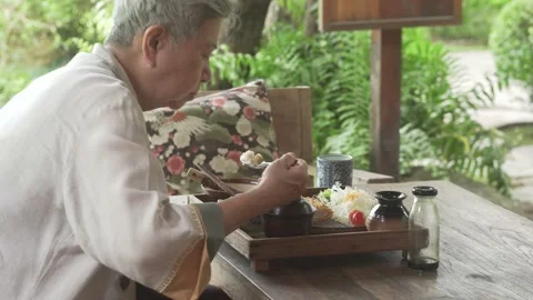 Old elderly senior elder woman eating fried pork rice japanese food on terrace Stock Footage 196228756