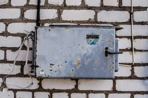 Old electric box on concrete wall with steel tube and plug / Smart Electric U Stock Photos