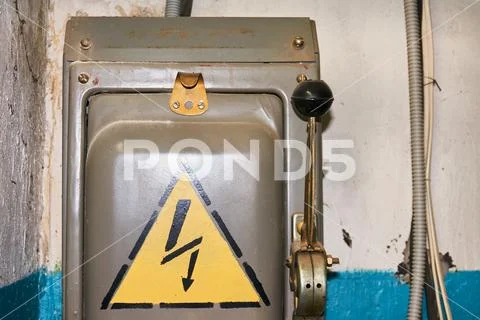 An old electric high-voltage switch with a painted danger sign. Stock Photos