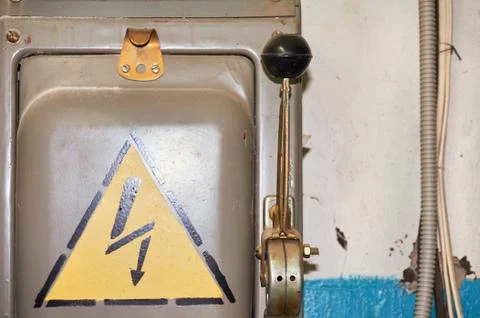 An old electric high-voltage switch with a painted danger sign. Stock Photos