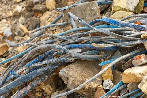 An old electrical cable sticks out of the ground against a backdrop of bricks Stock Photos