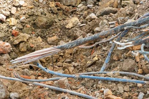 An old electrical cable sticks out of the ground against a backdrop of bricks Stock Photos