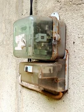 Old electrical meter box mounted on a wall, showing rusted metal parts Stock Photos